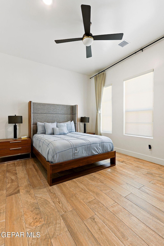 bedroom with visible vents, wood-type flooring, baseboards, and ceiling fan