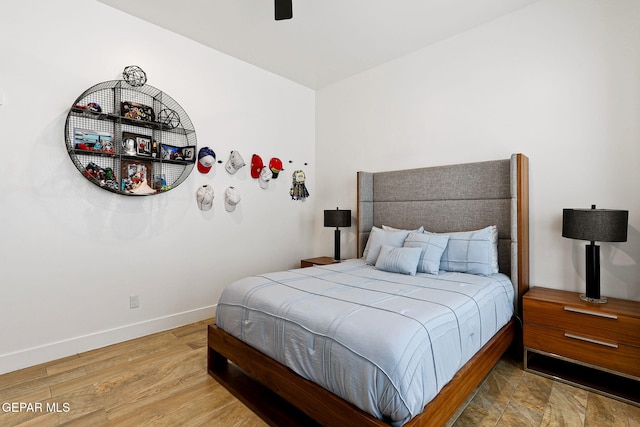 bedroom featuring baseboards, wood finished floors, and a ceiling fan