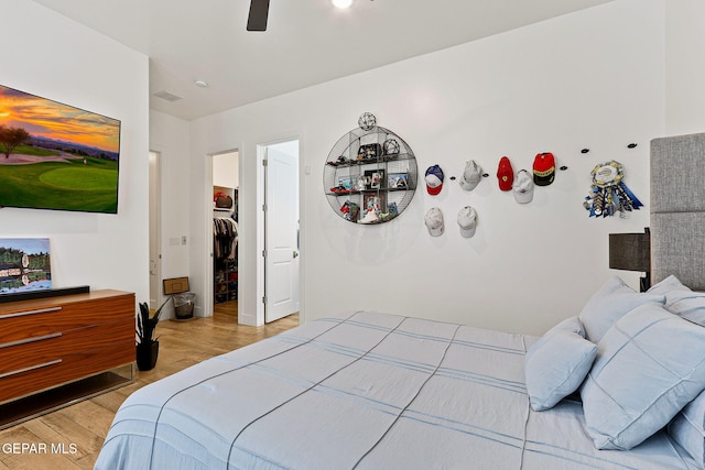 bedroom with light wood-style flooring, a spacious closet, a closet, and ceiling fan