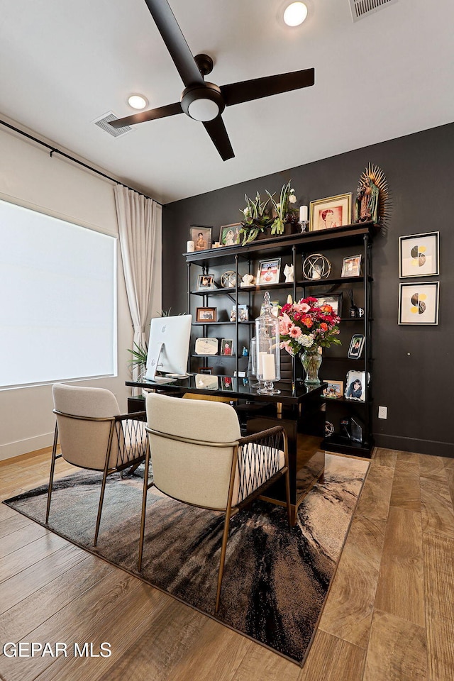 home office with visible vents, baseboards, wood finished floors, and a ceiling fan