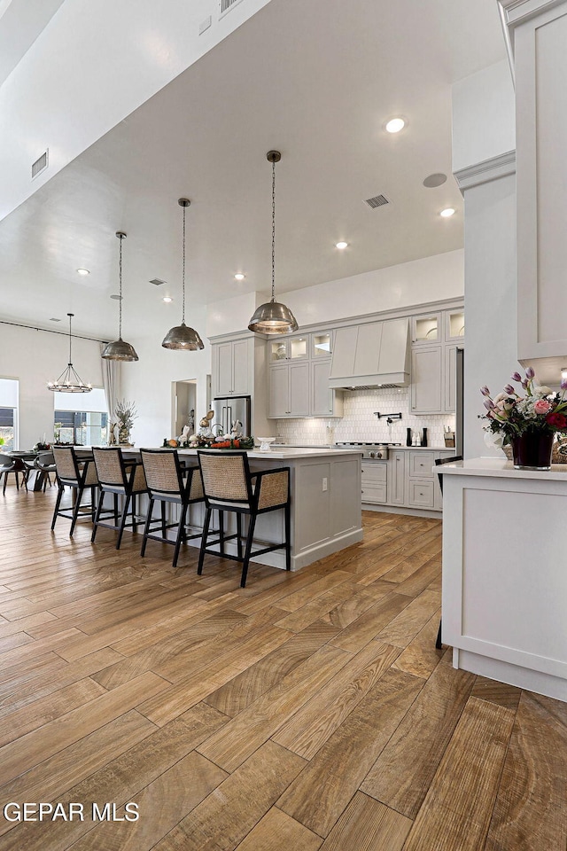 kitchen with visible vents, backsplash, light countertops, custom range hood, and stainless steel appliances