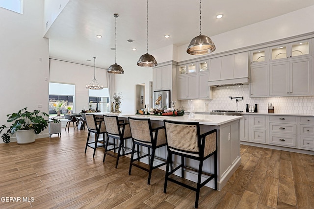 kitchen featuring dark wood finished floors, light countertops, a center island with sink, and backsplash