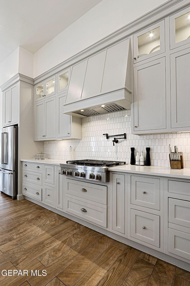 kitchen with custom range hood, tasteful backsplash, dark wood-style flooring, and stainless steel appliances