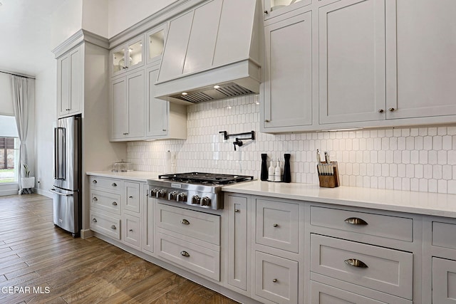 kitchen with custom exhaust hood, appliances with stainless steel finishes, light countertops, and dark wood-type flooring