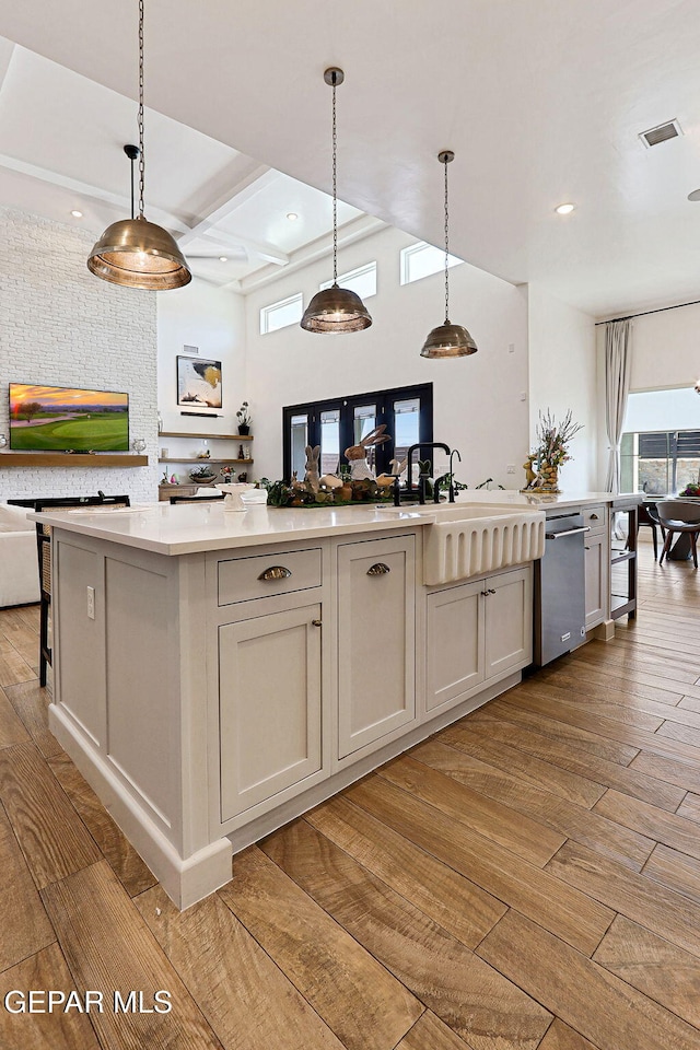 kitchen with a sink, stainless steel dishwasher, open floor plan, light wood-style floors, and light countertops