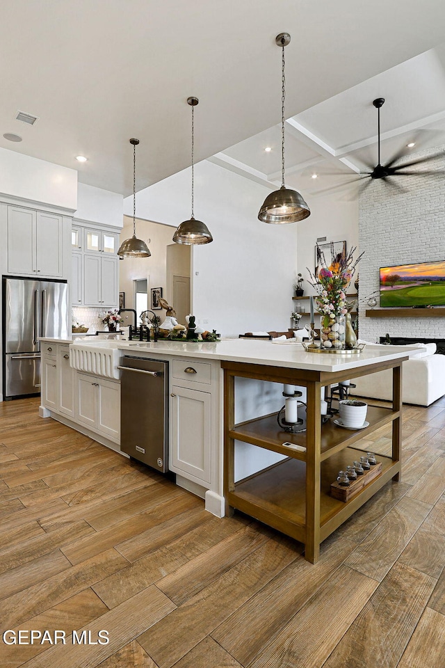 kitchen with light wood finished floors, visible vents, open floor plan, light countertops, and stainless steel appliances