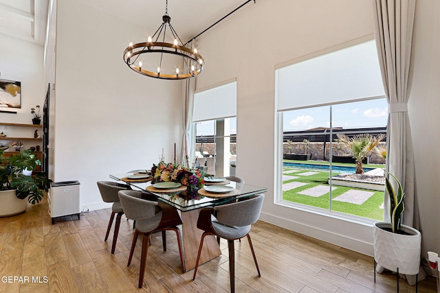 dining area with a wealth of natural light, a notable chandelier, and light wood-style floors