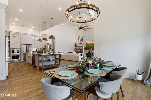 dining space with ceiling fan with notable chandelier, recessed lighting, and light wood-style floors