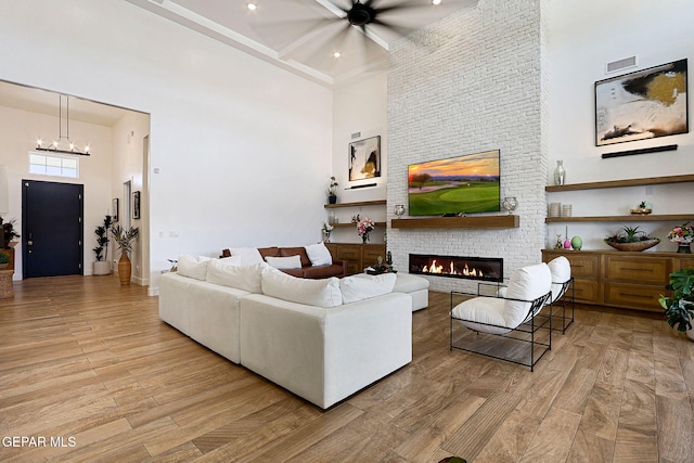 living area with visible vents, a fireplace, a towering ceiling, and wood finished floors