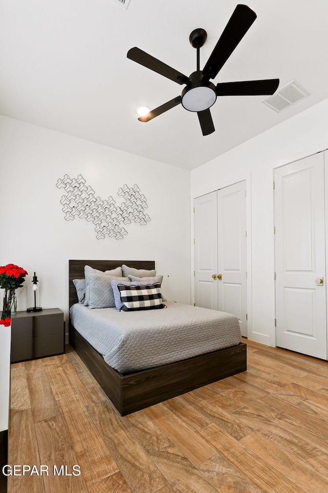 bedroom with a closet, visible vents, light wood finished floors, and ceiling fan