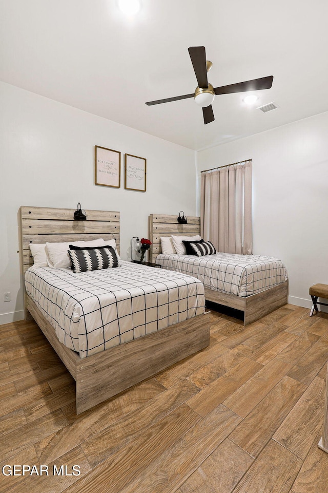 bedroom featuring visible vents, baseboards, wood finished floors, and a ceiling fan