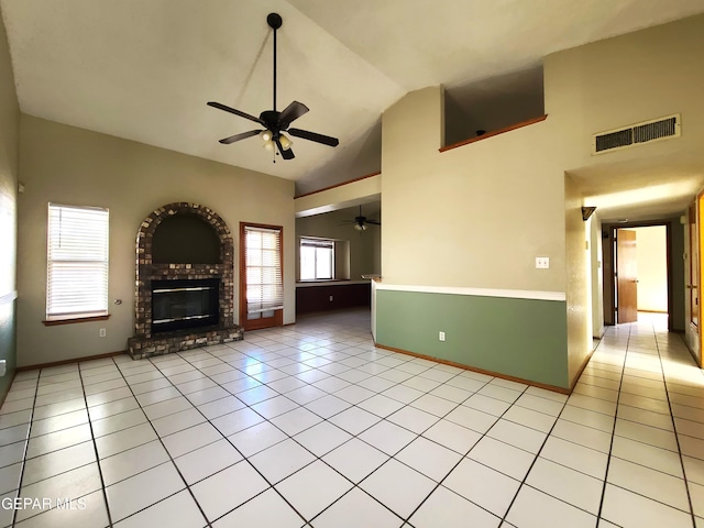 unfurnished living room with visible vents, a brick fireplace, ceiling fan, light tile patterned flooring, and high vaulted ceiling