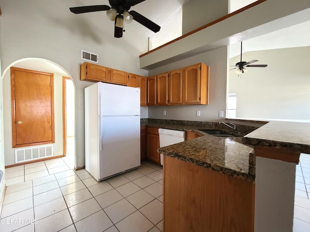 kitchen with visible vents, a peninsula, light tile patterned flooring, white appliances, and a sink