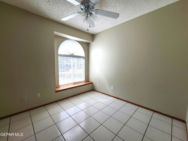 spare room featuring light tile patterned floors, baseboards, a textured ceiling, and a ceiling fan