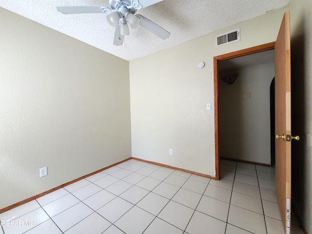 spare room with visible vents, a textured ceiling, light tile patterned floors, baseboards, and ceiling fan