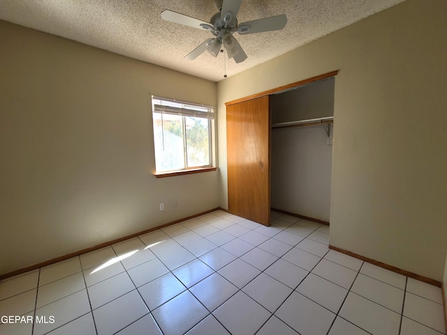 unfurnished bedroom featuring light tile patterned flooring, baseboards, a closet, and a textured ceiling