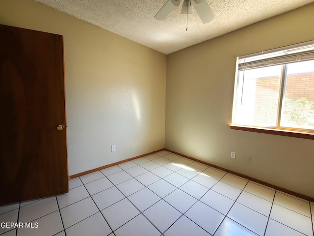 unfurnished room with light tile patterned floors, baseboards, a textured ceiling, and ceiling fan