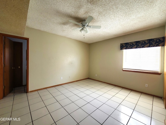 spare room featuring light tile patterned floors, a ceiling fan, baseboards, and a textured ceiling