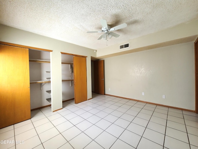 unfurnished bedroom featuring a ceiling fan, baseboards, visible vents, a textured ceiling, and two closets