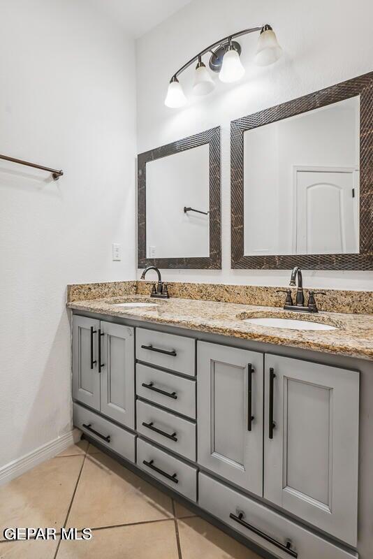 bathroom with tile patterned flooring, a sink, baseboards, and double vanity