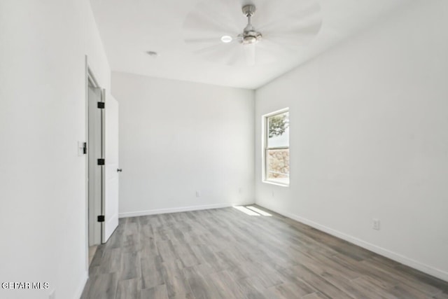 empty room with wood finished floors, a ceiling fan, and baseboards