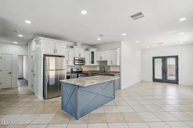 kitchen featuring appliances with stainless steel finishes, light tile patterned flooring, visible vents, and tasteful backsplash