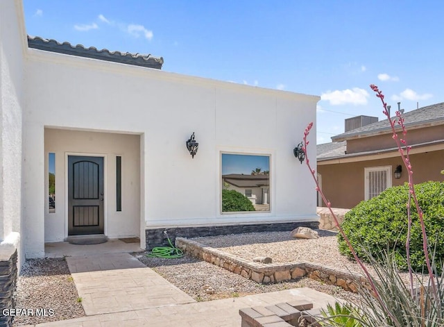 view of exterior entry with stone siding and stucco siding