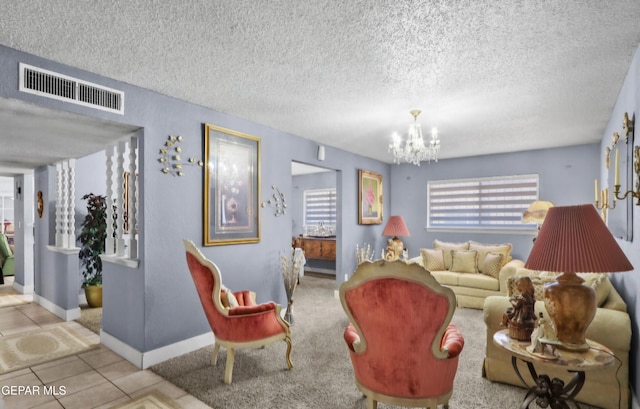 tiled living area with a textured ceiling, baseboards, visible vents, and a notable chandelier