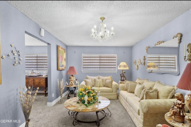 carpeted living area with a notable chandelier, a textured ceiling, and baseboards