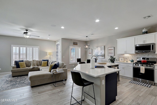 kitchen featuring visible vents, a sink, backsplash, appliances with stainless steel finishes, and light wood finished floors