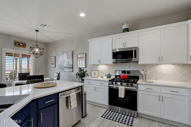 kitchen with visible vents, blue cabinetry, light countertops, stainless steel appliances, and white cabinetry