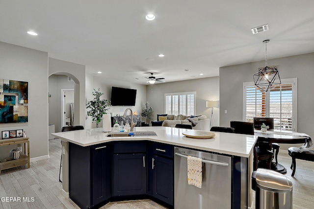 kitchen featuring visible vents, a kitchen island with sink, a sink, stainless steel dishwasher, and open floor plan