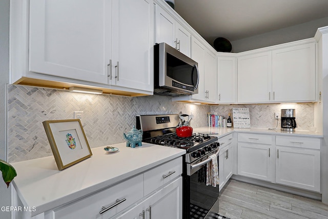 kitchen with decorative backsplash, white cabinets, appliances with stainless steel finishes, and light countertops