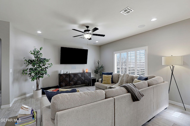 living room featuring visible vents, baseboards, light wood-style flooring, and a ceiling fan