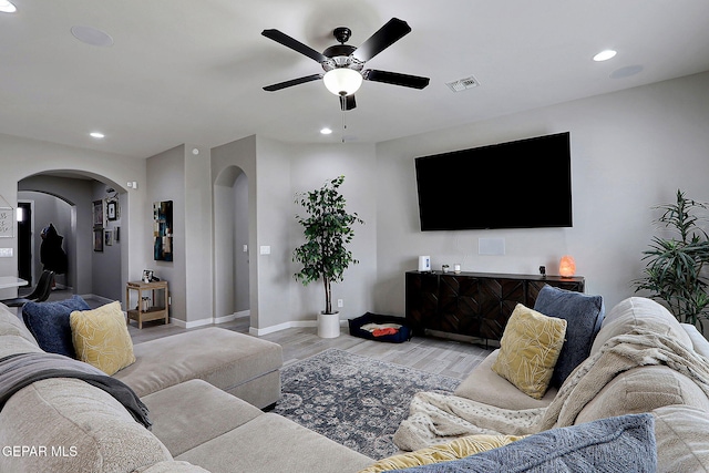 living room with recessed lighting, visible vents, arched walkways, and light wood-style flooring