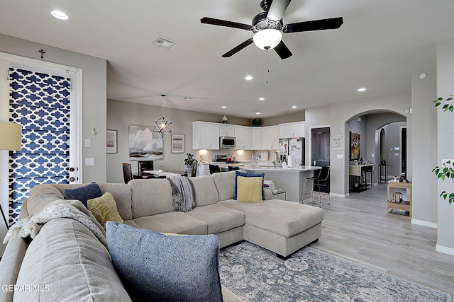 living room with a ceiling fan, visible vents, recessed lighting, arched walkways, and light wood-type flooring