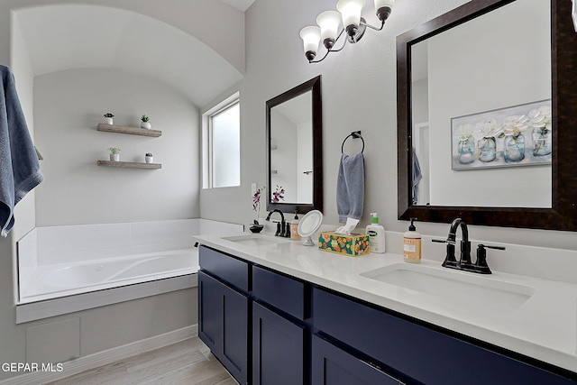 full bath with a sink, wood finished floors, a bath, and double vanity