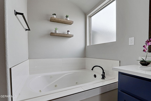 bathroom featuring vanity, vaulted ceiling, and a jetted tub