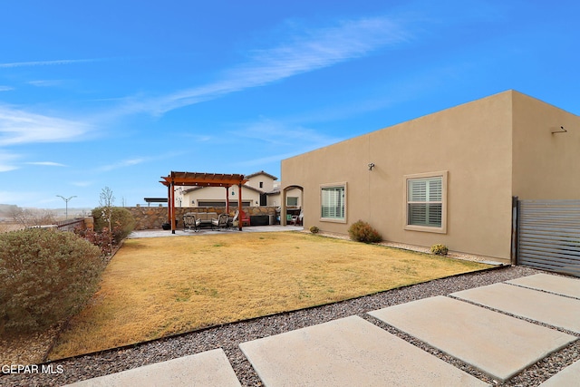 back of property with fence, stucco siding, a yard, a patio area, and a pergola