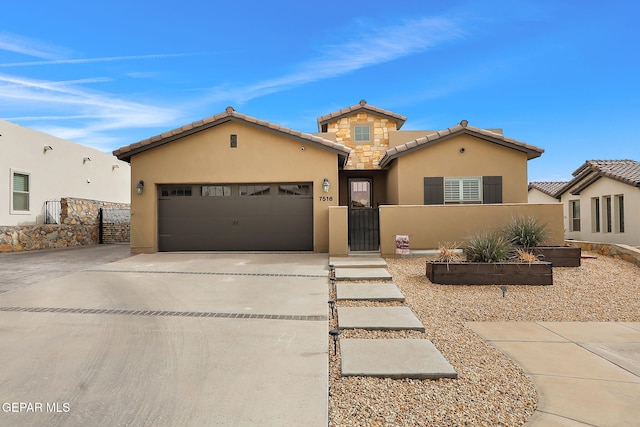 mediterranean / spanish-style house featuring stucco siding, an attached garage, a fenced front yard, and driveway