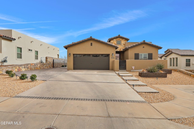 view of front facade with a gate, fence, driveway, stucco siding, and a garage