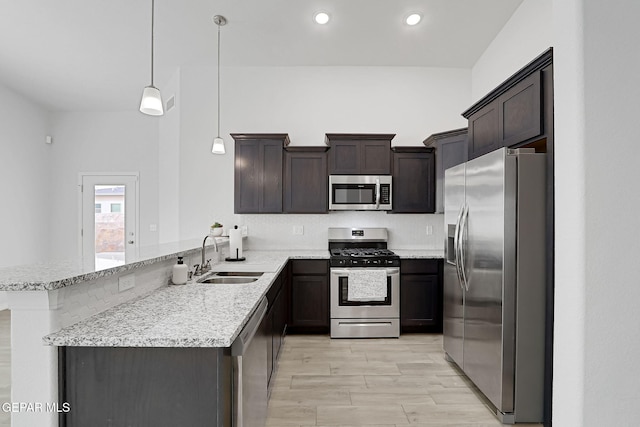 kitchen with a sink, a peninsula, dark brown cabinets, and stainless steel appliances