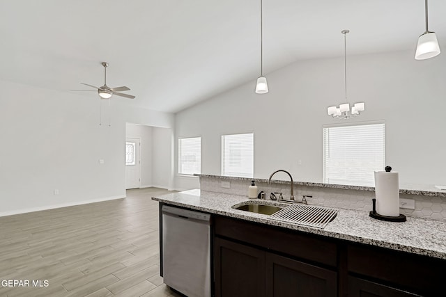 kitchen featuring lofted ceiling, a sink, light wood-style floors, stainless steel dishwasher, and decorative light fixtures