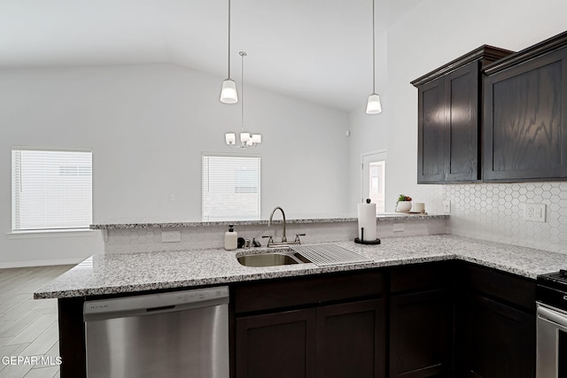 kitchen featuring vaulted ceiling, light stone counters, a peninsula, stainless steel appliances, and a sink