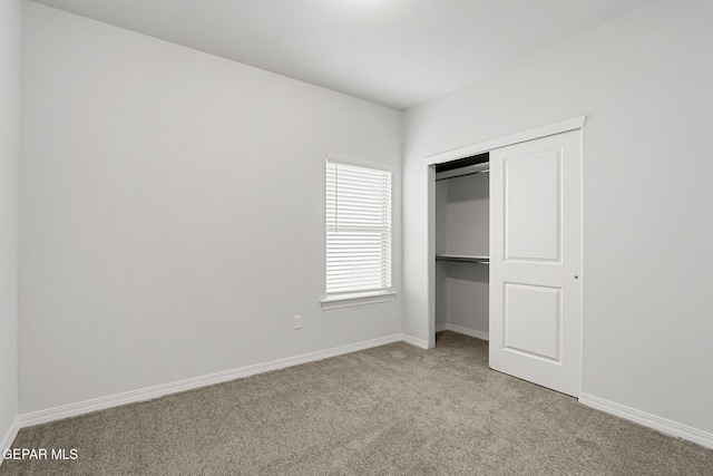 unfurnished bedroom with a closet, carpet flooring, and baseboards