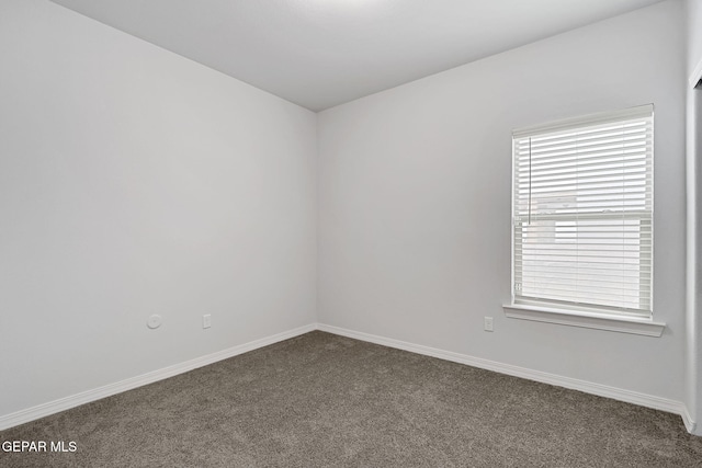 unfurnished room with baseboards and dark colored carpet