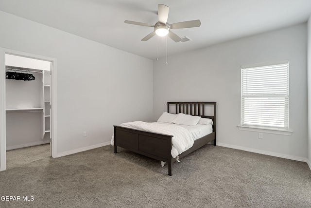 bedroom with baseboards, a walk in closet, carpet floors, and visible vents