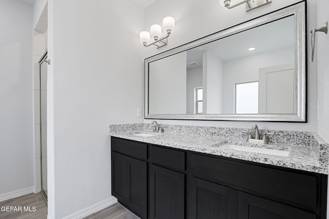 bathroom featuring double vanity, baseboards, wood tiled floor, and a sink