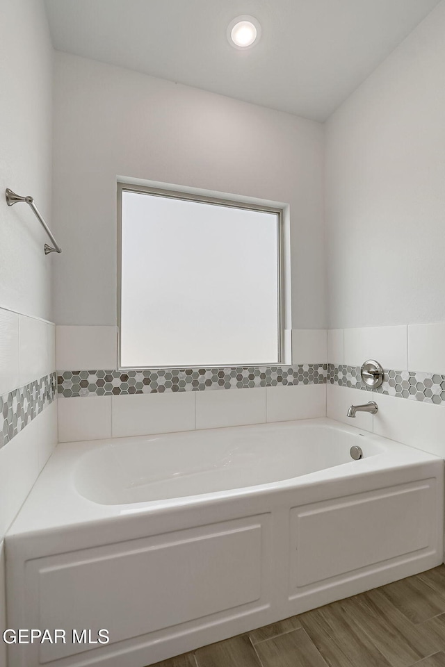 bathroom with a bath and wood finished floors