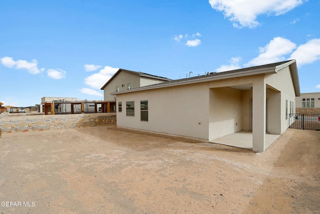 rear view of property with a patio area, fence, and stucco siding